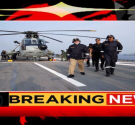 प्रधानमंत्री नरेंद्र मोदी INS विक्रांत पर नौसेना की शक्ति प्रदर्शन के दौरान सलामी देते हुए, पृष्ठभूमि में युद्धपोत और नौसैनिक टुकड़ियां।